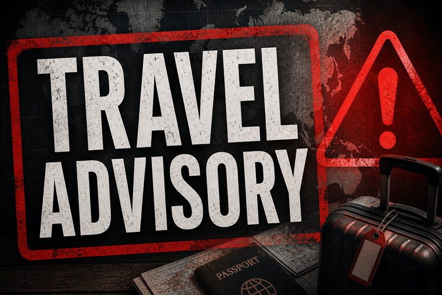 Red travel advisory sign with a warning triangle, a suitcase, and a passport on a wooden surface.